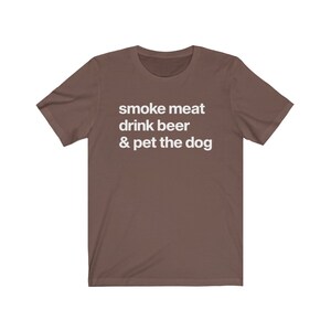 K&ouml;nnte beinhalten: Ein braunes T-Shirt mit dem Aufdruck "smoke meat drink beer & pet the dog" in wei&szlig;.