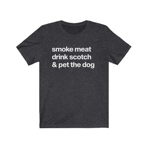 May include: Dark heather grey t-shirt with white text that reads "smoke meat drink scotch & pet the dog".