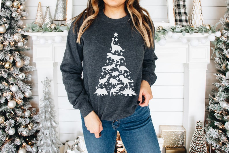 May include: A dark gray sweatshirt with a white silhouette of a Christmas tree made of dinosaurs. The tree is topped with a star.