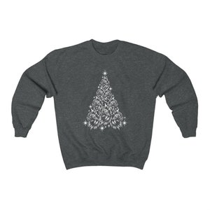 May include: A dark grey sweatshirt featuring a white design of a Christmas tree made up of cat faces. The tree has a star on top and is surrounded by small white stars.