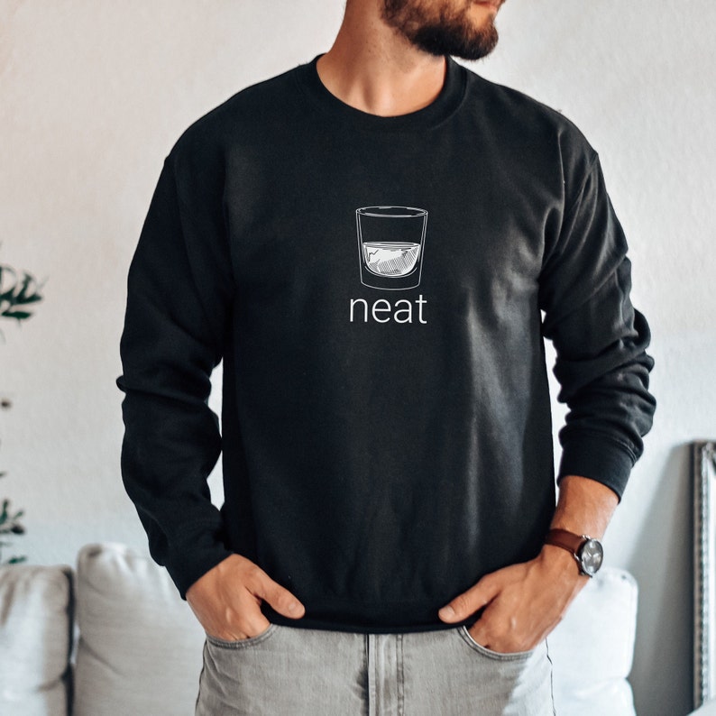 Pode incluir: Camisola de moletom preta com um gr&aacute;fico branco de um copo de licor e a palavra "neat" embaixo.