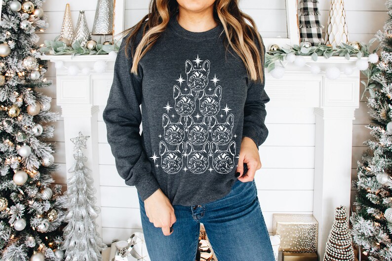 May include: A dark gray sweatshirt with a white outline of a Christmas tree made of French bulldog faces. The tree is decorated with stars.