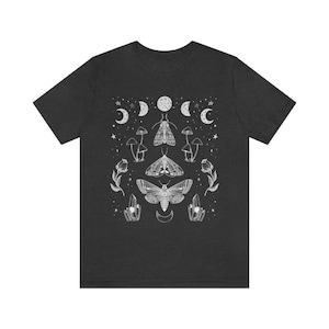 Puede incluir: Una camiseta gris oscuro con un dise&ntilde;o gr&aacute;fico blanco con polillas, hongos, cristales y lunas crecientes.