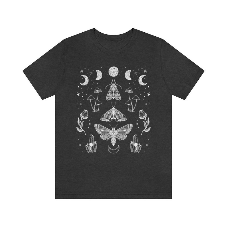 Puede incluir: Una camiseta gris oscuro con un dise&ntilde;o gr&aacute;fico blanco con polillas, hongos, cristales y lunas crecientes.