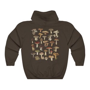 May include: A brown hoodie featuring a detailed illustration of various mushrooms in shades of brown, red, and green. The design is centered on the back of the hoodie. The hoodie has a hood and long sleeves.