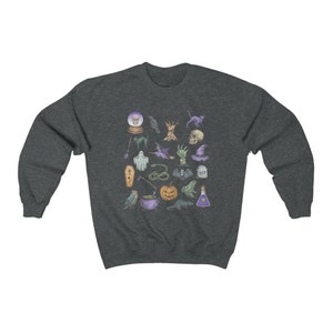 May include: A dark heather grey sweatshirt with a colorful graphic print of various Halloween-themed icons, including a skull, a cauldron, a ghost, a bat, a pumpkin, a cat, a snake, a spider, a witch's hat, a tree, a crow, a potion bottle, a crystal ball, a broom, a coffin, and a tombstone.