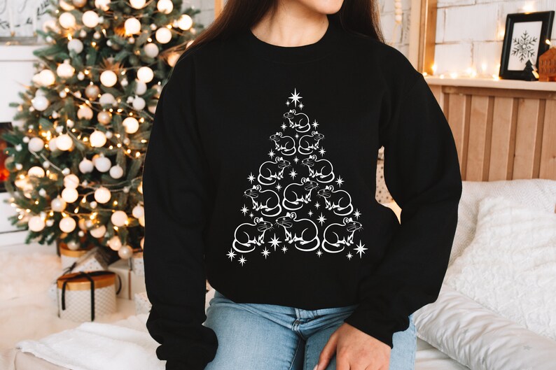 May include: A black sweatshirt with a white design of a Christmas tree made of rats. The tree is decorated with stars.