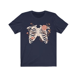 May include: Navy blue t-shirt with a white ribcage design surrounded by pink flowers and green leaves.