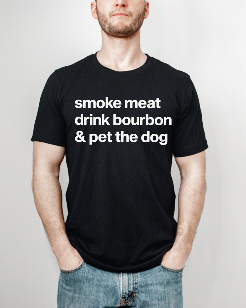 May include: A black t-shirt with white text that reads "smoke meat drink bourbon & pet the dog".