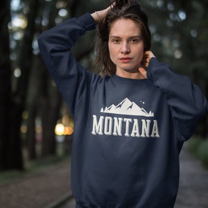 May include: A navy blue sweatshirt with a white mountain graphic and the text "MONTANA" in white.