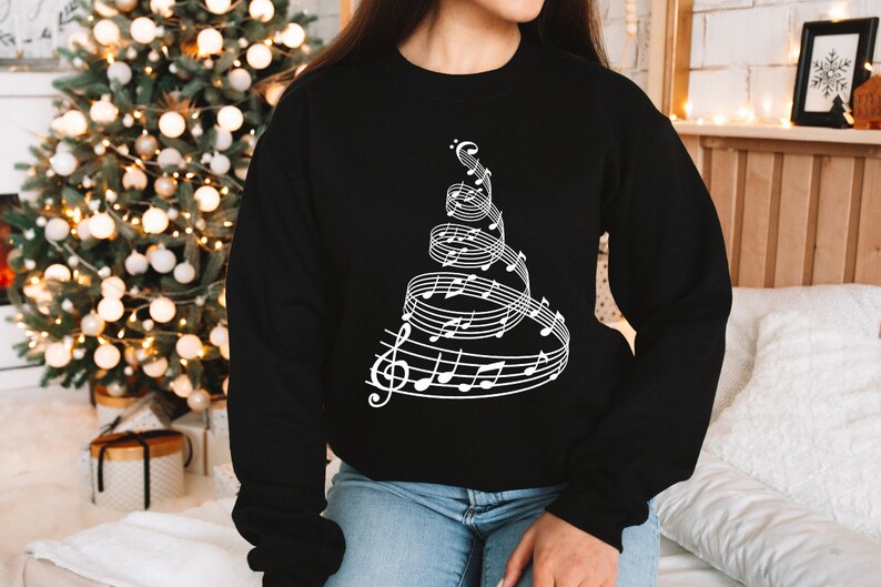 May include: Black sweatshirt with a white design of a Christmas tree made of musical notes.