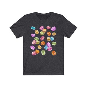 May include: A dark heather grey t-shirt with a colorful macaron pattern. The macarons are in various colors, including pink, blue, green, yellow, and orange.