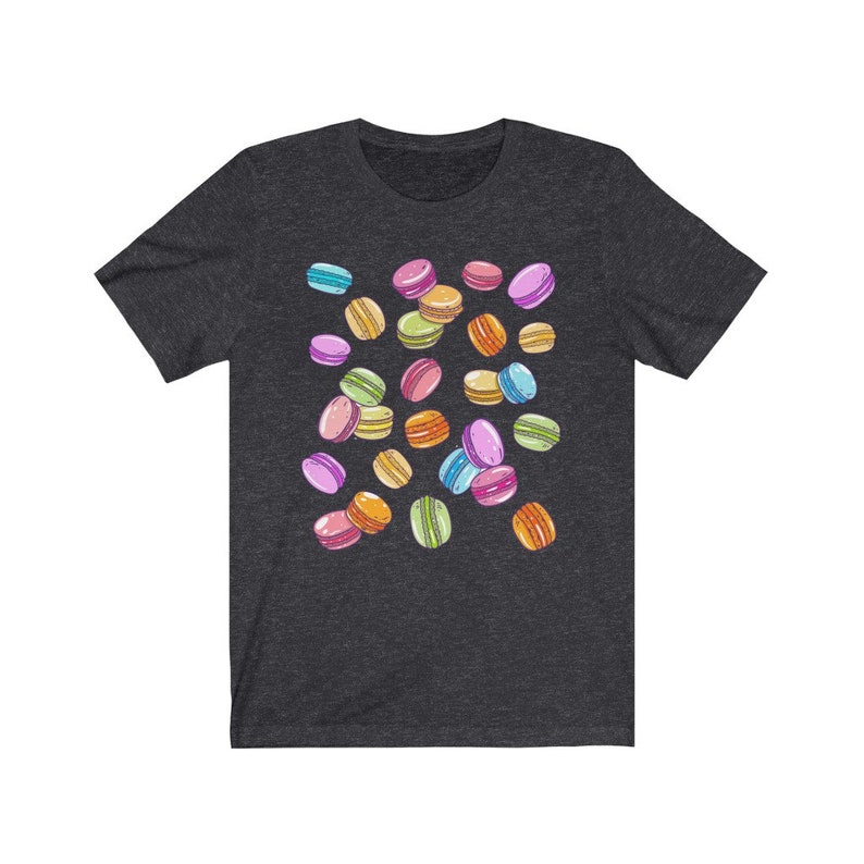 May include: A dark heather grey t-shirt with a colorful macaron pattern. The macarons are in various colors, including pink, blue, green, yellow, and orange.