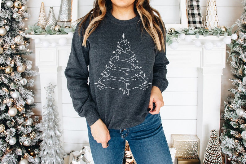 May include: A dark grey sweatshirt featuring a white outline of a Christmas tree made of pigs. The tree is topped with a star.