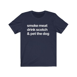 May include: A navy blue t-shirt with white text that reads "smoke meat drink scotch & pet the dog".