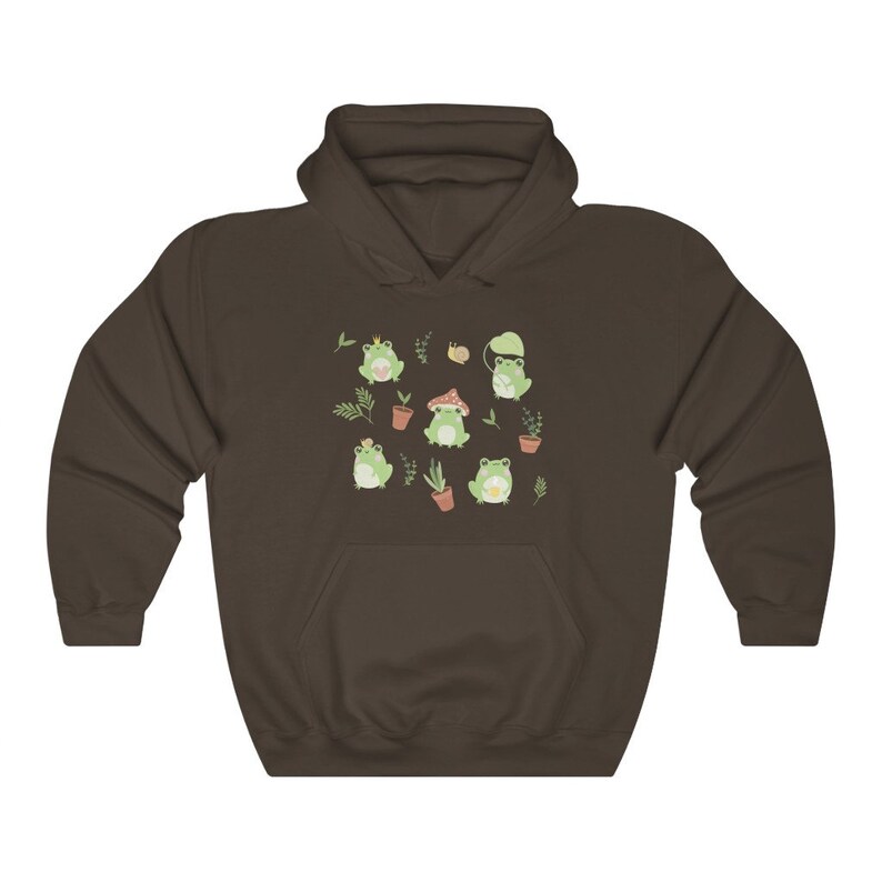 May include: A brown hoodie with a pattern of green frogs wearing crowns, hats, and sitting on mushrooms. The frogs are surrounded by green leaves and flowers.
