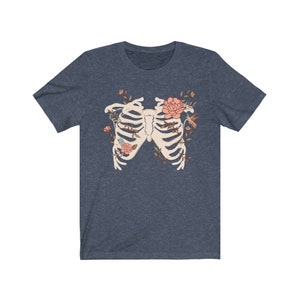 May include: A navy blue t-shirt with a white ribcage design surrounded by pink flowers and a hummingbird.