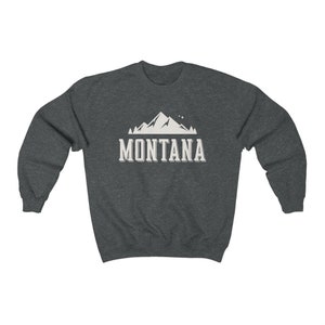 May include: A dark heather grey sweatshirt with a white mountain graphic and the text "MONTANA" printed on the front.