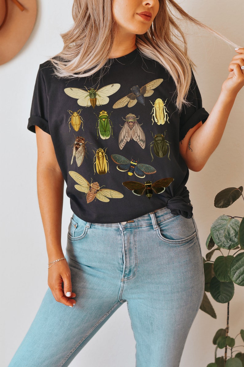 May include: A black t-shirt featuring a graphic print of various insects, including butterflies, beetles, and cicadas. The insects are depicted in a vintage style with detailed illustrations.