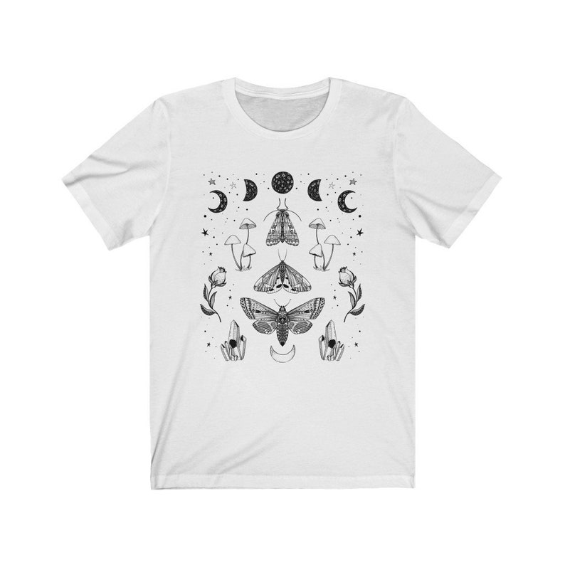 May include: White t-shirt with a black and white graphic design featuring moths, mushrooms, crystals, and moons.