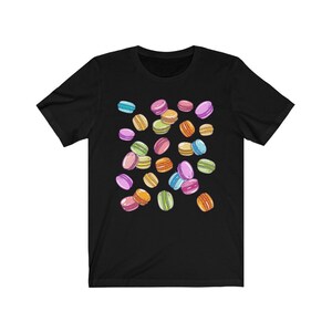 May include: A black t-shirt with a colorful pattern of macarons. The macarons are in various shades of pink, blue, green, yellow, and orange.
