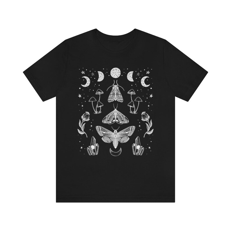 Puede incluir: Camiseta negra con un dise&ntilde;o gr&aacute;fico blanco con polillas, hongos, cristales y lunas.