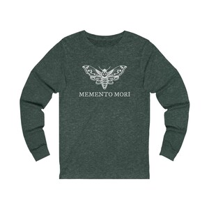 May include: A dark green long-sleeved t-shirt featuring a white moth graphic and the text "MEMENTO MORI" printed on the front.