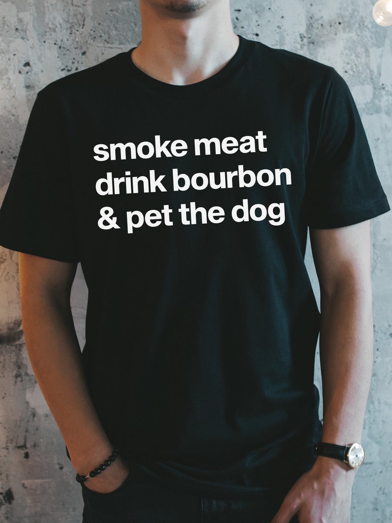 May include: A black t-shirt with white text that reads "smoke meat drink bourbon & pet the dog".