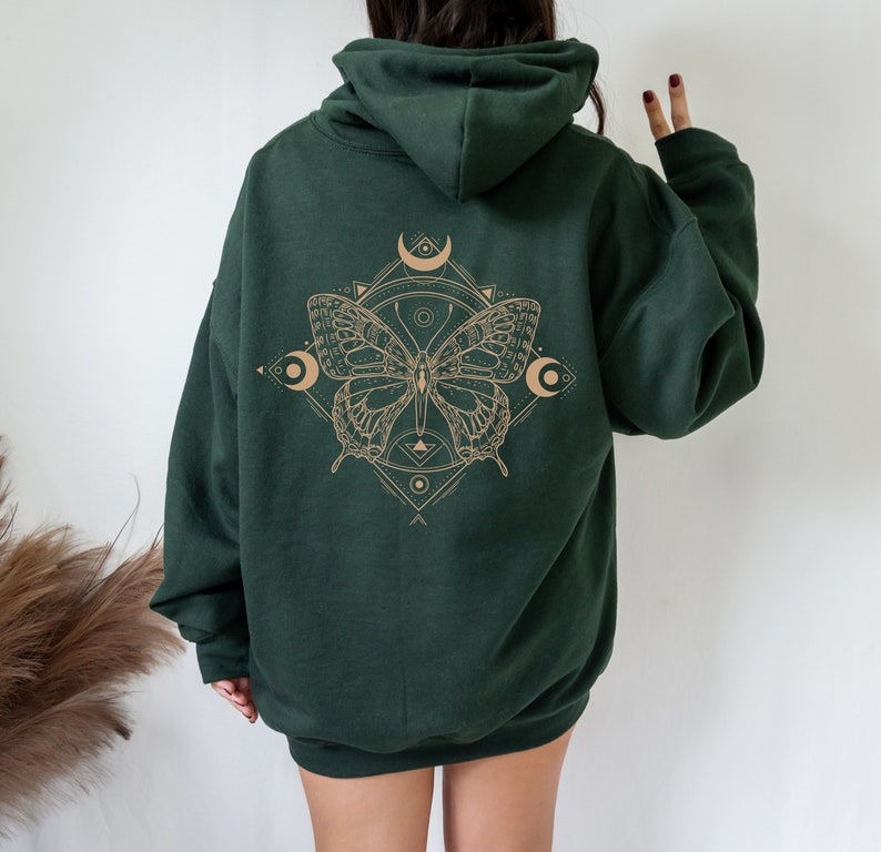 May include: A dark green hooded sweatshirt with a graphic print of a butterfly with geometric shapes and crescent moons in a light brown color.