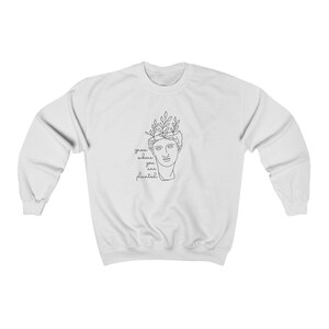 May include: White sweatshirt with a black line drawing of a bust with plants growing out of the top. The text "grow where you are planted" is below the drawing.