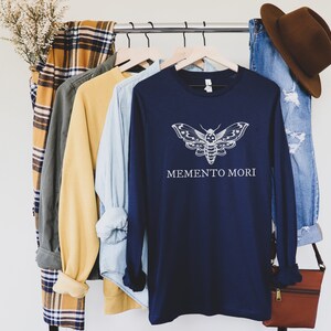 May include: Navy blue long-sleeved shirt with a white moth graphic and the text "Memento Mori".