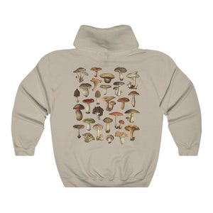 May include: A beige hoodie featuring a detailed illustration of various mushrooms in shades of brown, red, and green. The design is centered on the back of the hoodie, showcasing a variety of fungi species. The hoodie has a classic hooded design.