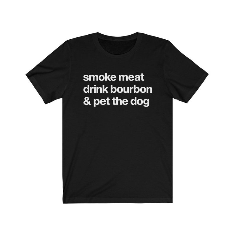 May include: Black t-shirt with white text that reads "smoke meat drink bourbon & pet the dog"