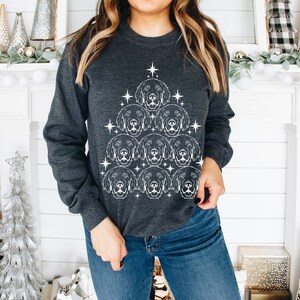 May include: A dark gray sweatshirt with a white design of a Christmas tree made up of dog faces. The tree is decorated with white stars.