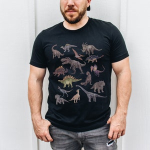 May include: A black t-shirt with a graphic print of various dinosaurs in different colors and poses. The dinosaurs are arranged in a random pattern on the shirt.