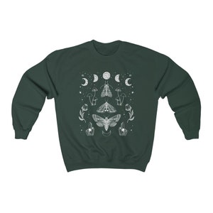 May include: A dark green sweatshirt with a white graphic design featuring moths, moons, mushrooms, and crystals.