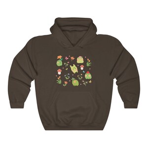 May include: A brown hooded sweatshirt with a pattern of green frogs, flowers, and mushrooms. The frogs are wearing hats and some are holding flowers.