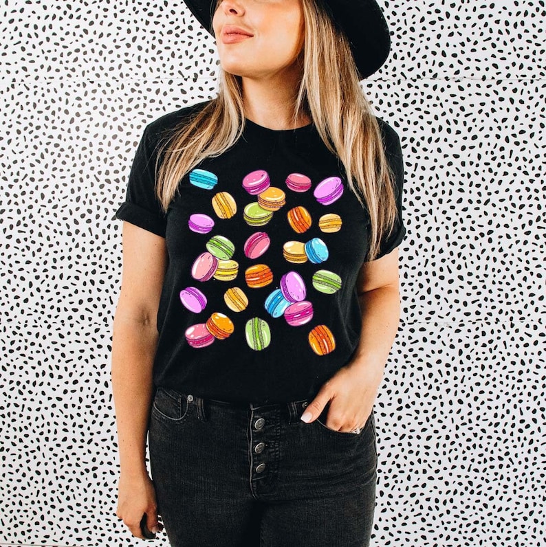 May include: A black t-shirt with a colorful macaron pattern. The macarons are pink, green, yellow, and blue.