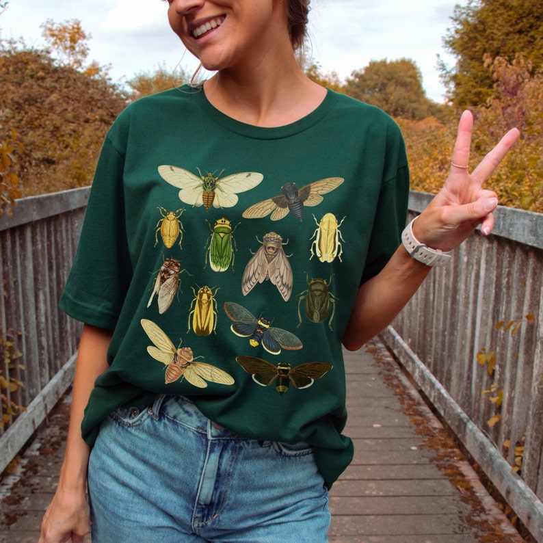 May include: A dark green t-shirt featuring a vintage illustration of various insects, including butterflies, beetles, and cicadas.