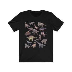 May include: Black t-shirt with a colorful illustration of various dinosaurs. The dinosaurs are arranged in a random pattern on the shirt.