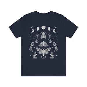 Puede incluir: Una camiseta azul marino con un dise&ntilde;o gr&aacute;fico blanco con polillas, setas, cristales y lunas.