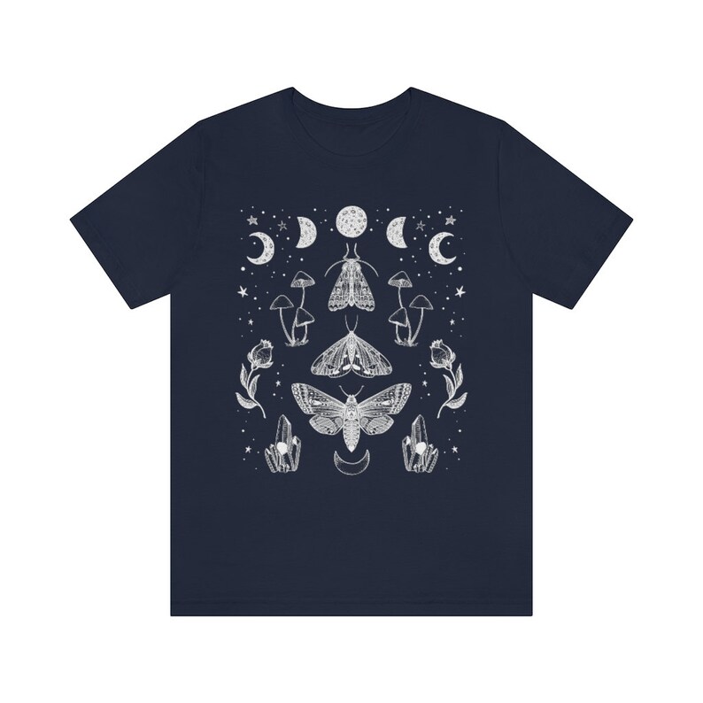 Puede incluir: Una camiseta azul marino con un dise&ntilde;o gr&aacute;fico blanco con polillas, setas, cristales y lunas.