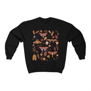 Puede incluir: Sudadera negra con un patr&oacute;n colorido de polillas, cristales y flores. El dise&ntilde;o presenta una variedad de especies de polillas, incluyendo polillas luna, polillas cecropia y polillas io.
