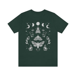 Puede incluir: Una camiseta verde oscuro con un dise&ntilde;o blanco con polillas, hongos, cristales y lunas.