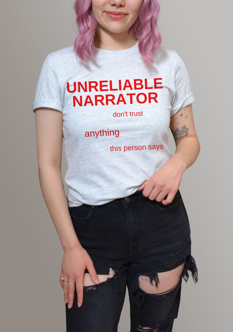 Puede incluir: Una camiseta gris claro con el texto "UNRELIABLE NARRATOR don't trust anything this person says" impreso en rojo.