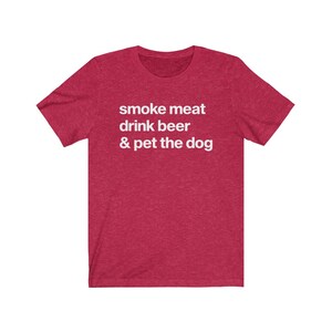 K&ouml;nnte beinhalten: Rotes T-Shirt aus Mischgewebe mit wei&szlig;em Text, der "smoke meat drink beer & pet the dog" lautet