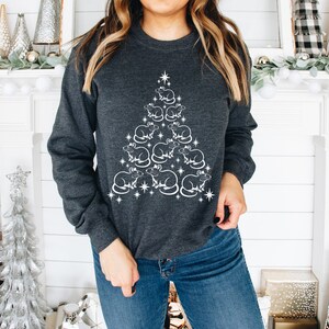 May include: A dark gray sweatshirt with a white design of a Christmas tree made of rats. The tree is decorated with stars.