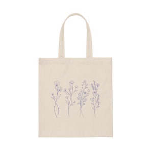 May include: A natural canvas tote bag with a design of five blue line drawings of different wildflowers.
