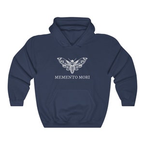 K&ouml;nnte beinhalten: Ein marineblauer Hoodie mit einem wei&szlig;en Motiv eines Schmetterlings mit Totenkopfdesign und dem darunter gedruckten Text "MEMENTO MORI".