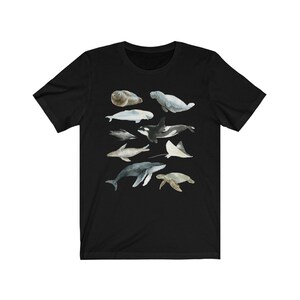 K&ouml;nnte beinhalten: Schwarzes T-Shirt mit einer Aquarell-Illustration verschiedener Meerestiere, darunter ein Wal, ein Delfin, eine Meeresschildkr&ouml;te, ein Seekuh und ein Rochen.